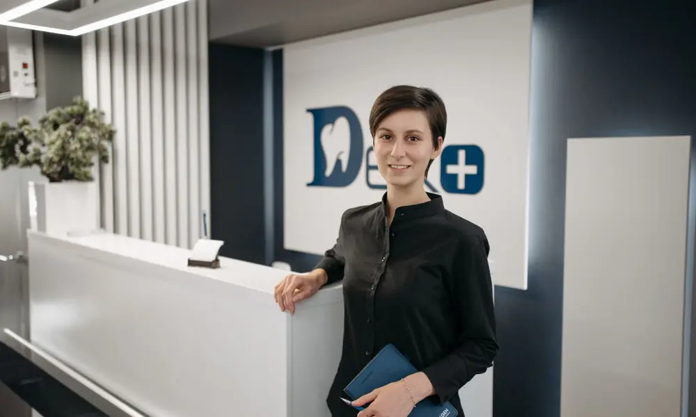 Una recepcionista sonríe tras el mostrador de una clínica dental