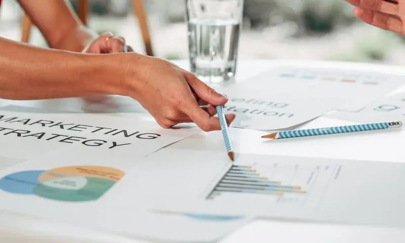 Manos señalando gráficas impresas de una estrategia de marketing